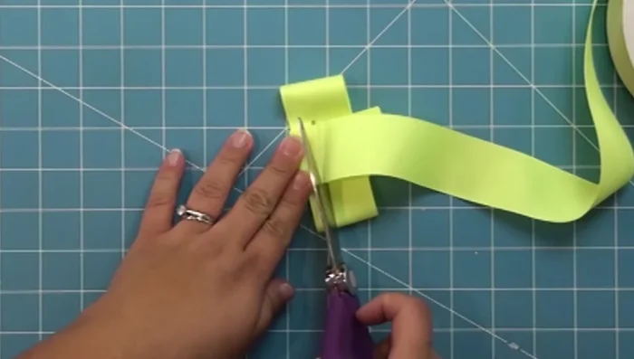 Measure a piece of ribbon to wrap around the center of the bow. Fold it to create a valley and two peaks, securing with a clothespin.