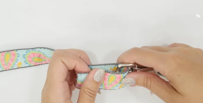 Attach handle. At the other end, slip on a D-ring (optional, skip if not making treat bag). Fold over 7 1/2 inches, ensuring raw edges align with the swivel hook. Fold under a quarter inch and stitch across multiple times. Stitch the D-ring securely into its own pocket.