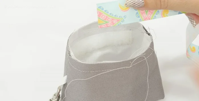 Attach ribbon. Pin ribbon to the inside of the treat bag, 3/8 inch down from the top edge. Baste stitch to secure. Fold one ribbon end under and layer on top of the other. Fold the top of the overlapping ribbon over to the right side and pin/top stitch.