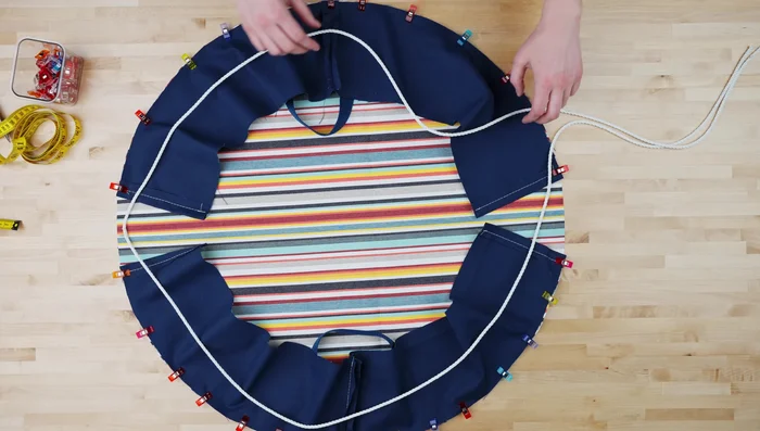 Cut 15 feet of rope in half; loop around edges, fold fabric strip over rope, and pin.