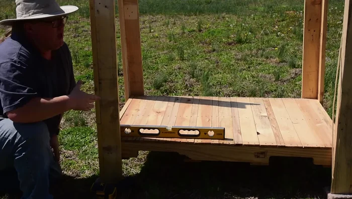 Install the roof: Mark a line 29 inches up on each leg to serve as a ledge for the roof. Clamp or partially drive nails into the legs at that mark. Position the roof pallet, ensuring level alignment, and secure it using nails.