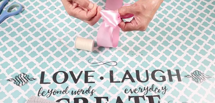 Create a bow from the pink ribbon by looping, pinching, and wrapping thread around the center. Hot glue (sewing recommended) the bow to the top side near the collar.