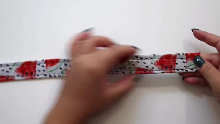 Attach the D-ring to the other end of the strap by sliding it through and pulling the strap through the buckle. Sew the strap to the sides of the D-ring to secure it.