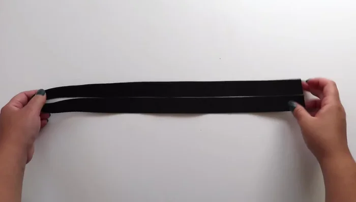 Cut your fabric to 3.75 inches wide and long enough to cover the strap's length. Press a 1-inch fold on one end and sew a basting stitch 2 inches from the hem (optional: use an iron to create the guides).