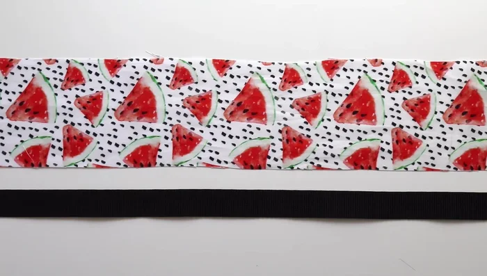 Cut your fabric to 3.75 inches wide and long enough to cover the strap's length. Press a 1-inch fold on one end and sew a basting stitch 2 inches from the hem (optional: use an iron to create the guides).