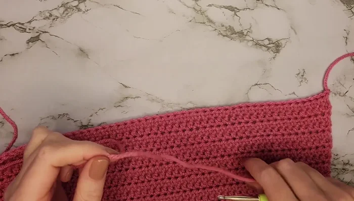 Fold the sweater in half, skip seven stitches, and half double crochet into the next stitch across the row (44 stitches total).