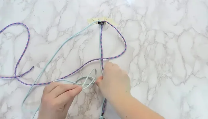 Add the D-ring to the bottom of the collar before continuing the square knot.