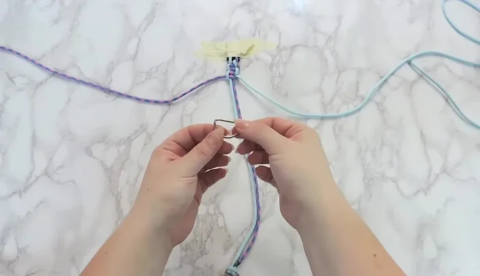 Add the D-ring to the bottom of the collar before continuing the square knot.