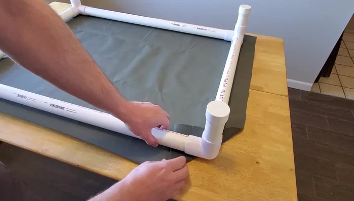 Fold and secure the fabric corners: Fold the corners of the fabric over to clear the corner fittings. Use clamps to hold fabric in place while you check for evenness.