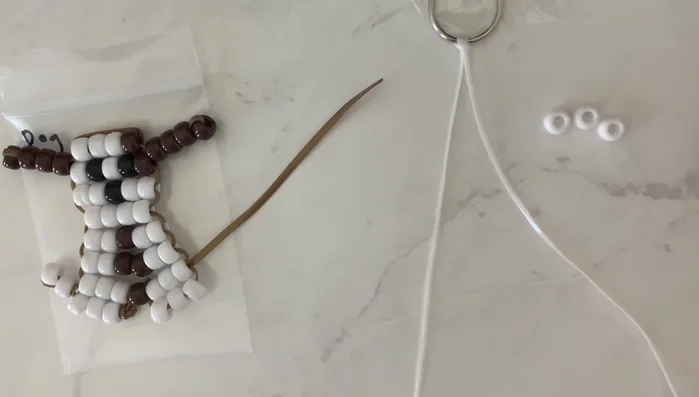 Attach the second string: Thread the other end of your string (without beads) through the beads of the first row, ensuring both strings run through each bead. This creates a horizontal row.