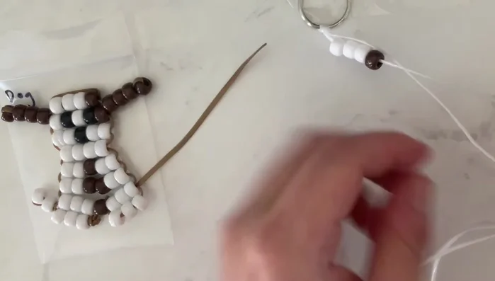 Attach the second string: Thread the other end of your string (without beads) through the beads of the first row, ensuring both strings run through each bead. This creates a horizontal row.