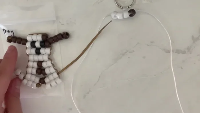 Create the ears: For each ear, string three brown beads onto one string. Thread the same string through the *other* three beads on the string, creating a loop. Repeat for the second ear.