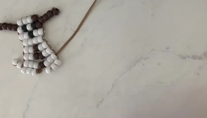 Prepare the keychain loop: Tie a loop at one end of the string, and thread the keychain ring through the loop. Tighten securely, optionally using tape to hold the ring in place while you work.