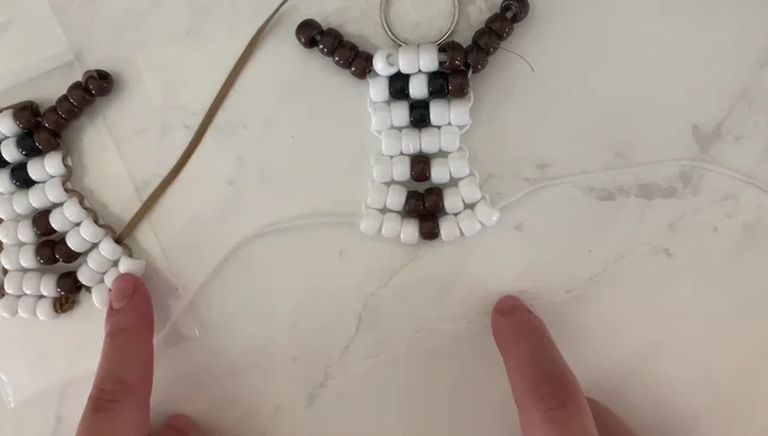 Create the paws: String three white beads onto one string for each paw. Instead of using the second string, thread the same string back through the last three beads to create a small loop for each paw.