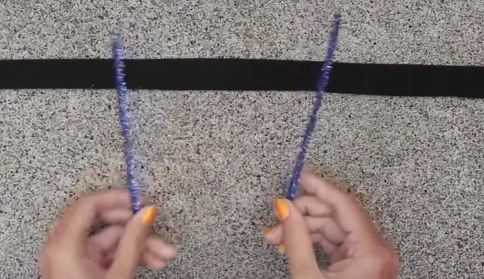 Fold a pipe cleaner in half, cut, and wrap around a pencil to create antennas. Glue a pom-pom to the top.