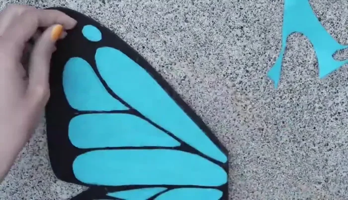 Cut small circle pieces from felt and glue them onto the wing to create a pattern; repeat with white felt.