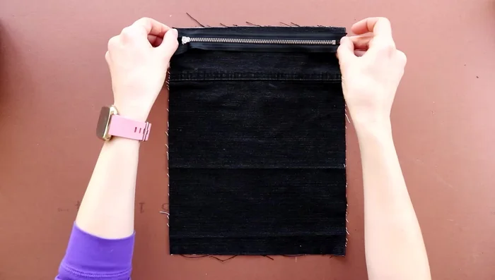 Sew down the fold, close to the zip.