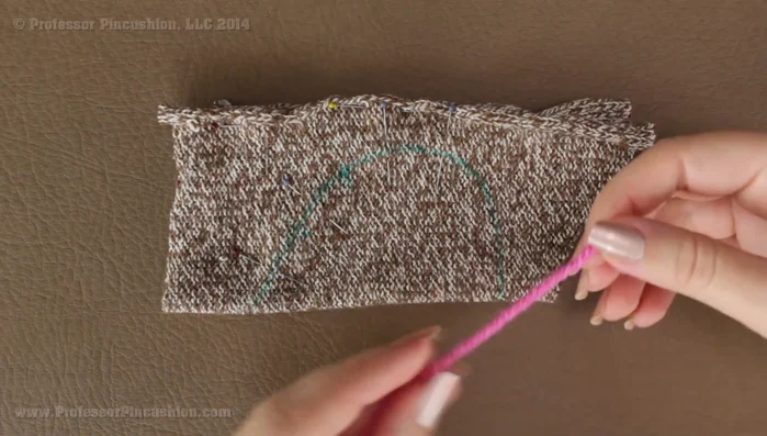 Place the tail yarn (approx. 4 inches) inside the sock, aligning with the bottom fold line. Sew only the single yarn strand to the sock, leaving the rest free for the tail.