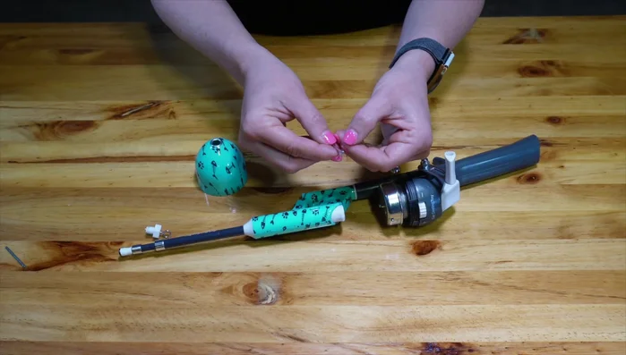 Put the weight through the top of the reel and fasten it back on.