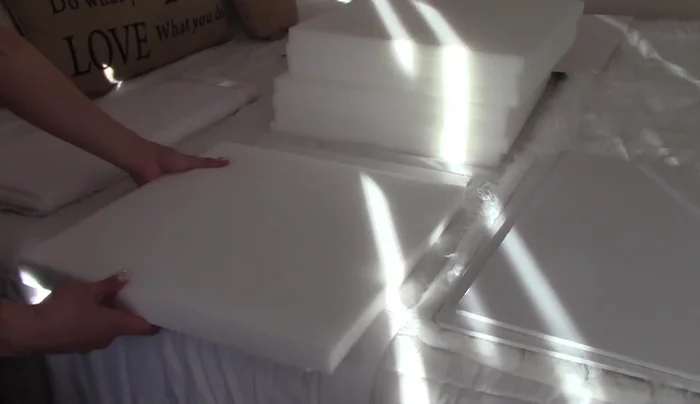 Cover the foam frame with white fabric, tucking and gluing the edges for a clean finish.