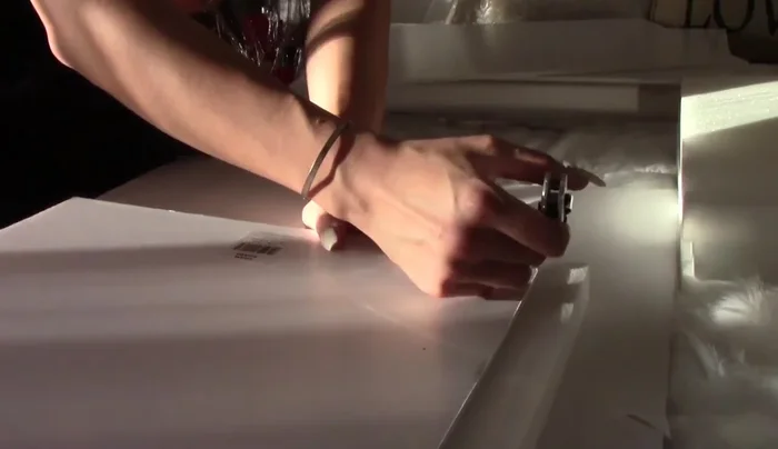 Cover the foam frame with white fabric, tucking and gluing the edges for a clean finish.