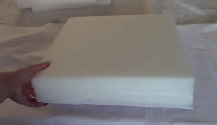 Cover the foam frame with white fabric, tucking and gluing the edges for a clean finish.