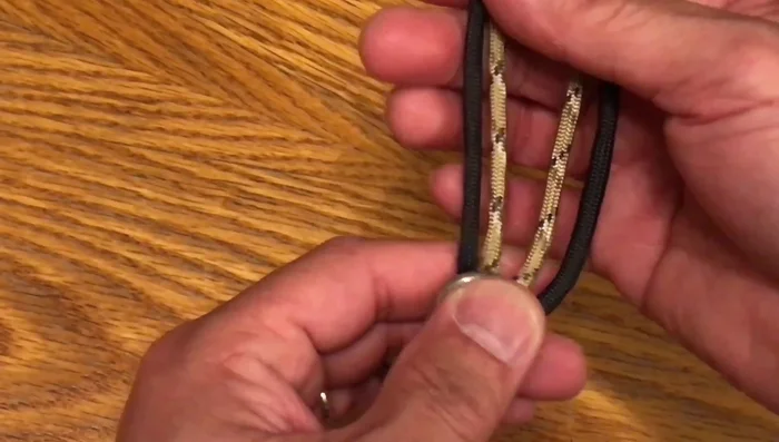 Create a tight knot using the alternating paracord strands, tucking each strand under and into the loop.