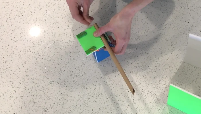 Attach the elastic bands, connecting the platform pieces to the box. Ensure it is snug but not too tight.