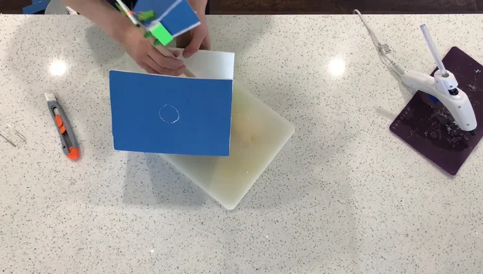 Cut a hole in the box to fit the mechanism and adjust box size as needed.