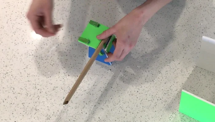 Glue two more double-layered popsicle stick pieces to either side of the platform, for the elastic to attach to.