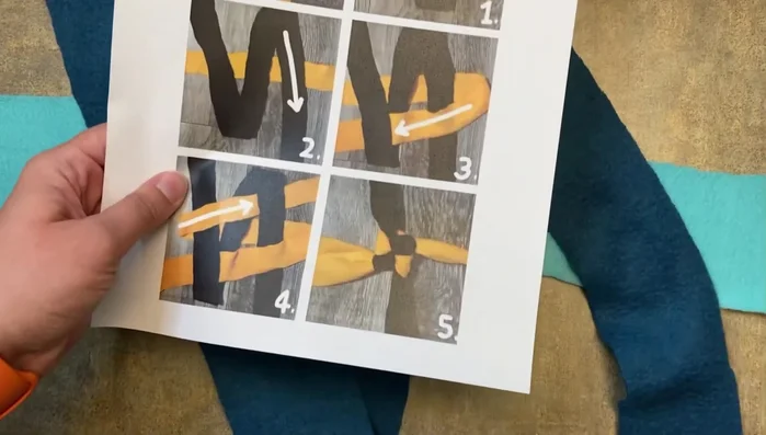 Take the leftmost piece of the horizontal fleece strip, pull it over the middle vertical piece, and then through the rightmost vertical piece to create a square knot.