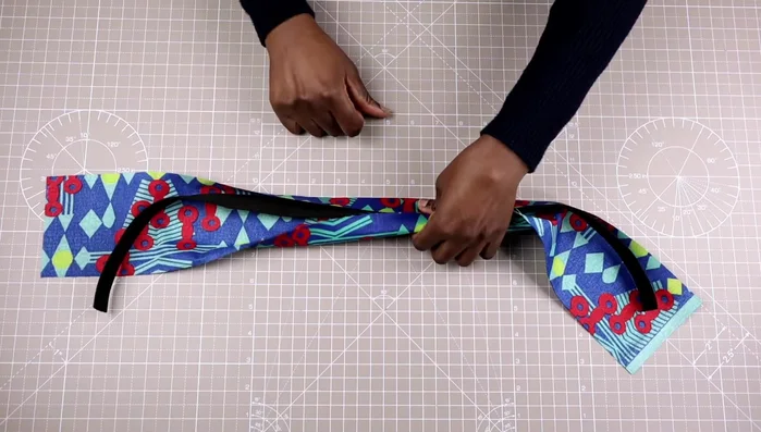 Prepare the fabric: Cut four times the width of the webbing (4 inches if webbing is 1 inch wide). Fold the fabric in half, iron to create a crease, and fold the edges inward to meet at the center.