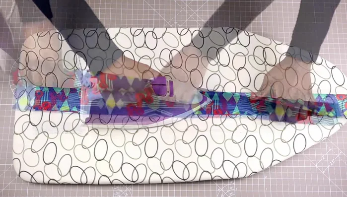 Insert webbing: Place the webbing into one of the folds and overlap the other fold. Ensure fabric is at least an inch longer than the webbing (28 inches fabric for 27 inches webbing in this example). Secure with clips.